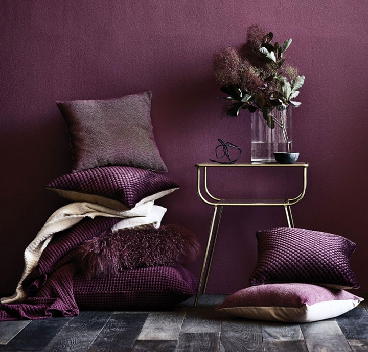 Dormitorio color morado estilo clásico con cojines y flores secas
