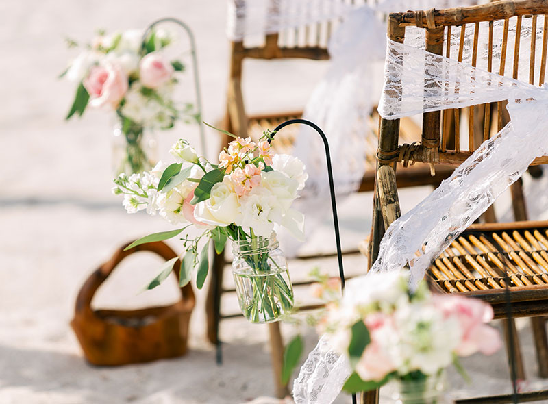 Sillas de bambú decoradas con flores en una boda al aire libre