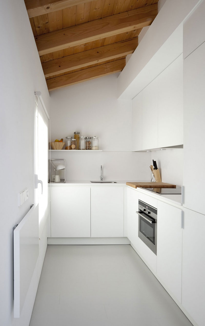 Una cocina blanca alargada y rectangular de estilo minimalista