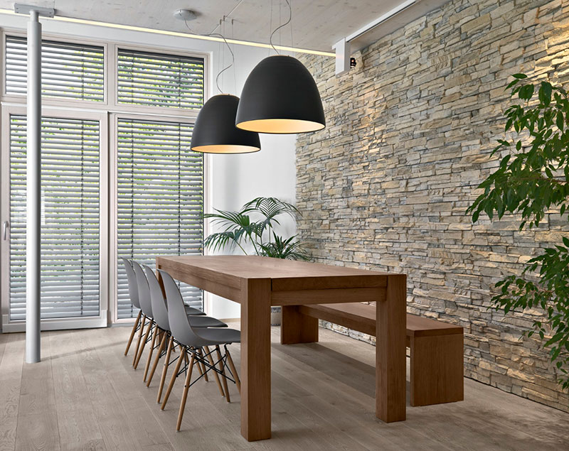 Comedor moderno con pared de piedra y lámparas de techo de diseño