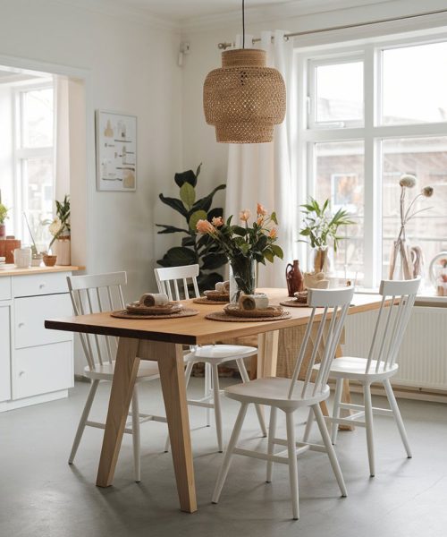 Mesa de comedor de madera con sillas blancas, lámpara colgante, suelo de microcemento y decoración escandinava acogedora